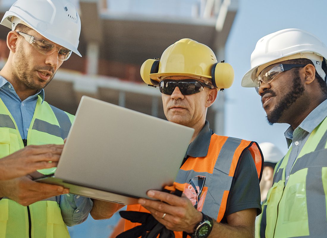 Insurance by Industry - Group of Engineers Review Plans on a Laptop at a Project Site